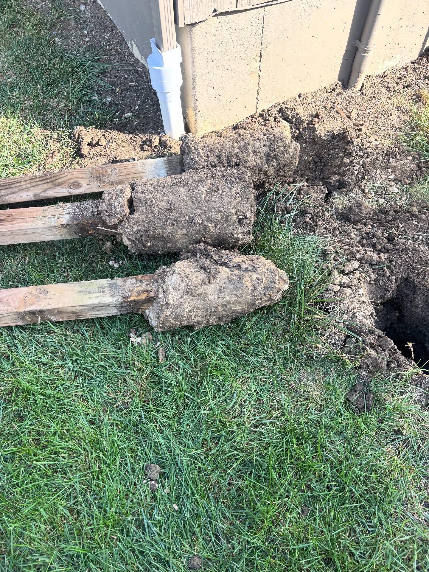 Wood fence post rotting at the soil line from poor drainage and no stain in Kansas City — RKC Wood Care Pros