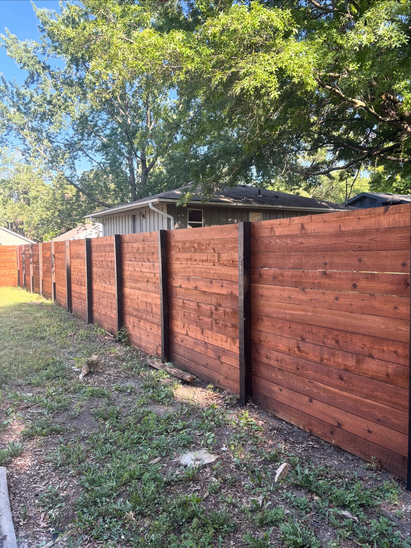 Stained horizontal wood fence with metal posts rebuilt in a Kansas City backyard — RKC Wood Care Pros