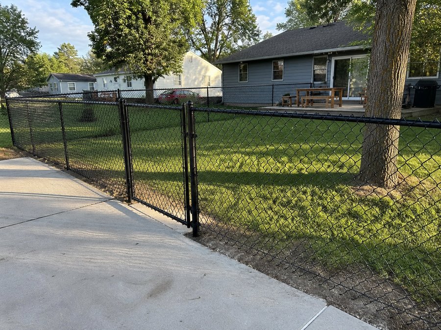 Black vinyl-coated residential chain link fence with walk gate in a Kansas City neighborhood — RKC Wood Care Pros