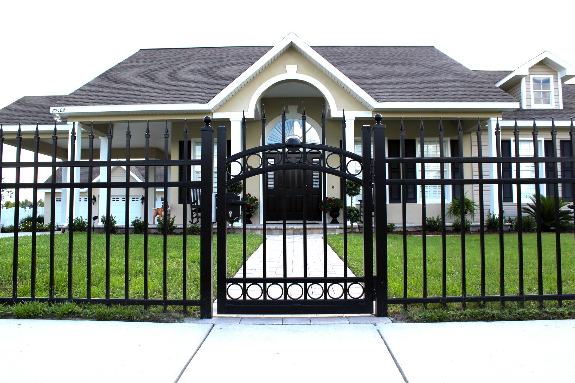 Black ornamental iron fence with decorative arched walk gate and ring accents at a Kansas City front yard — RKC Wood Care Pros