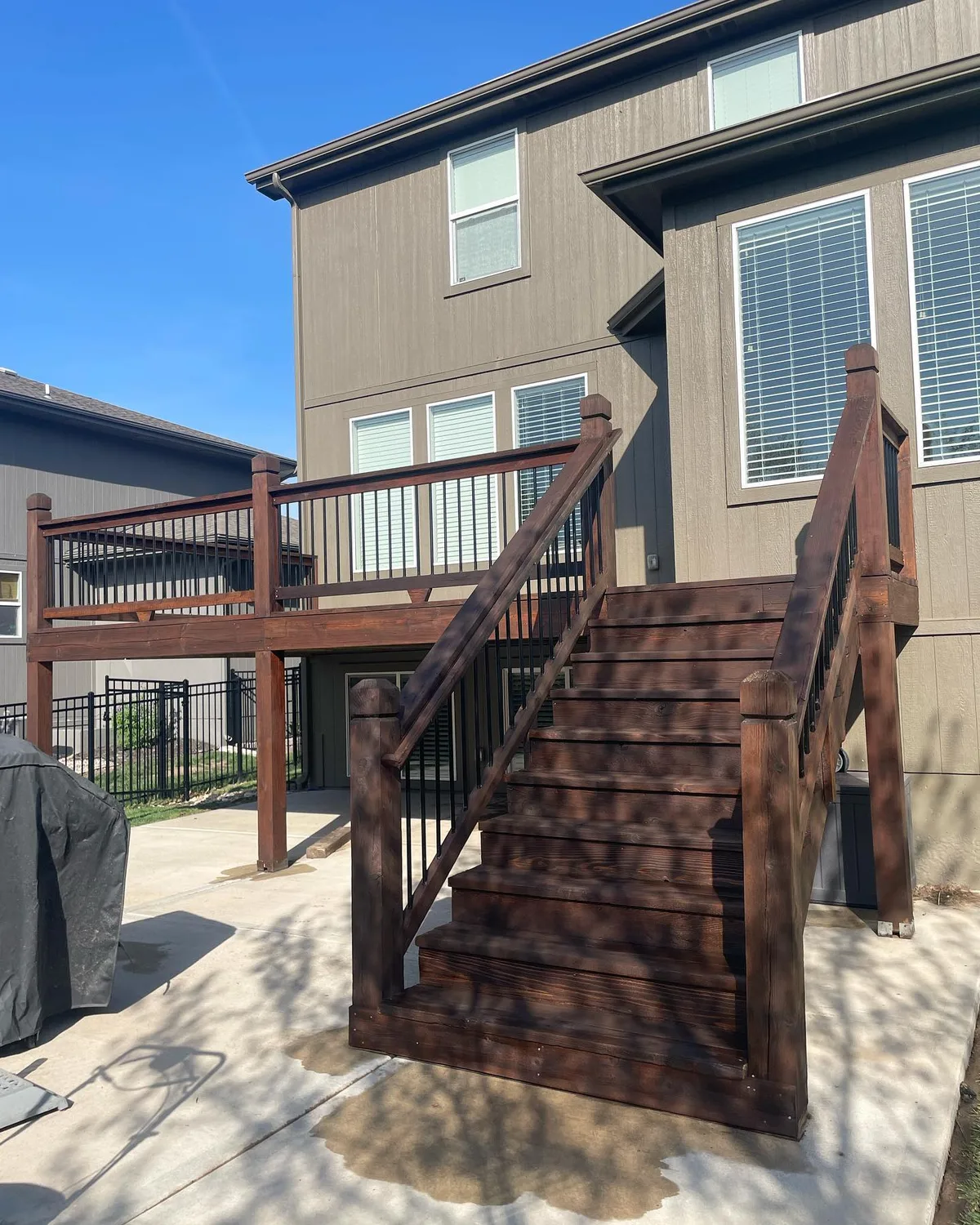 Wide view of freshly stained covered deck with cedar railing in Lenexa, KS
