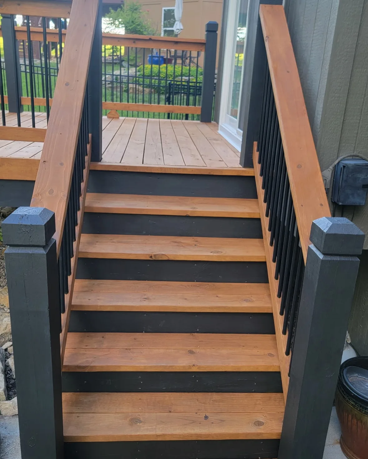 Cedar deck and staircase stained in two-tone amber and dark trim in Mission, KS — summer afternoon